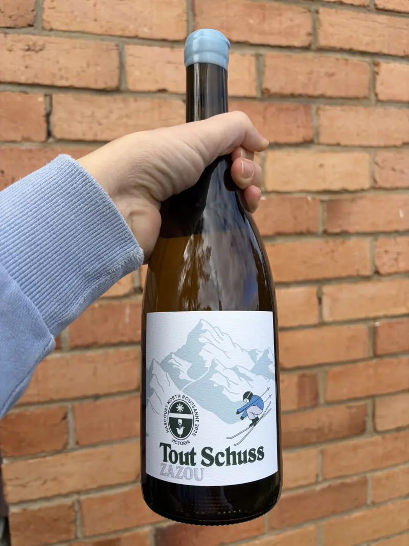 A bottle of Tout Schuss held against a brick wall
