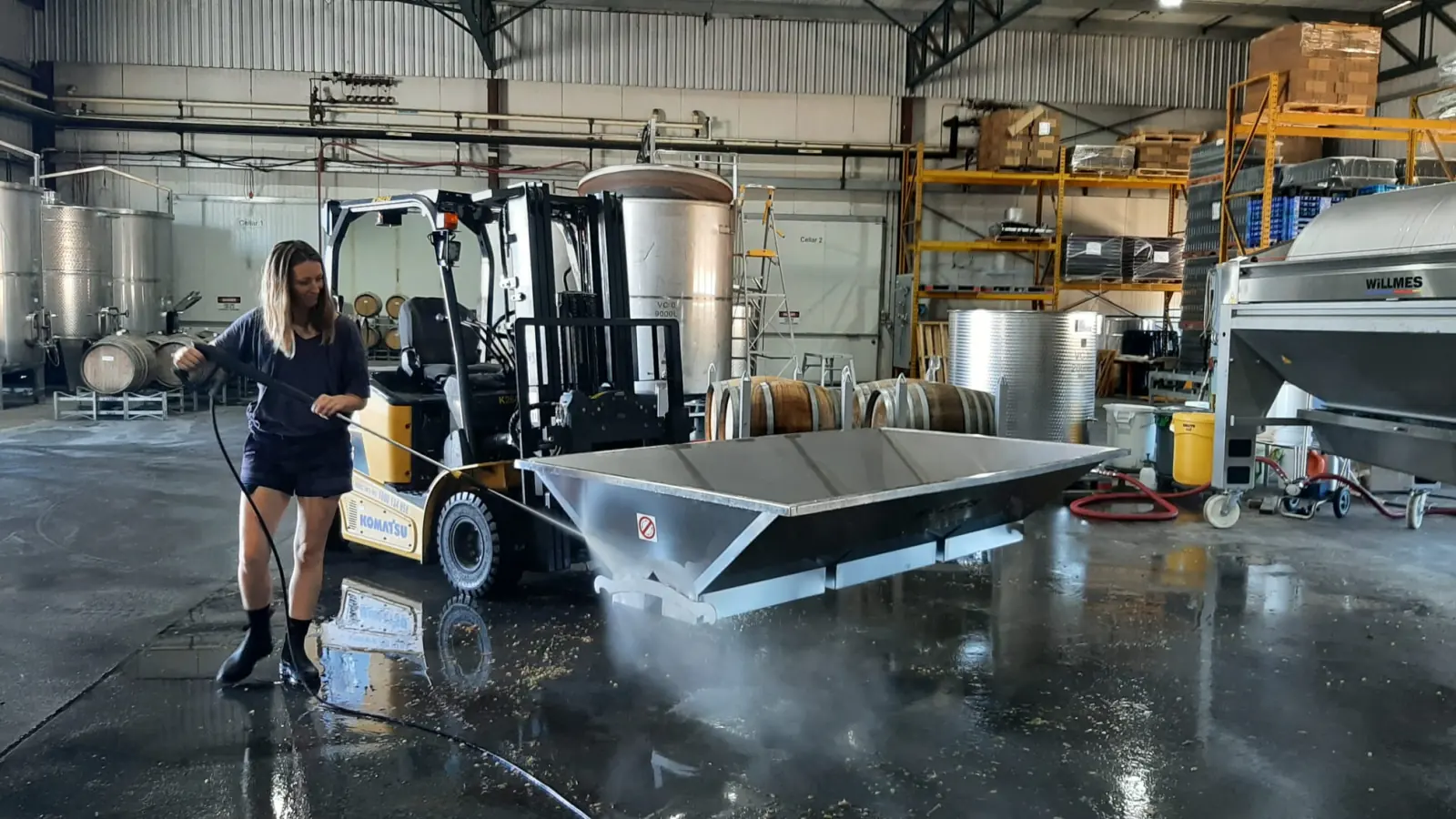 Hosing down the winery floor beside a forklift